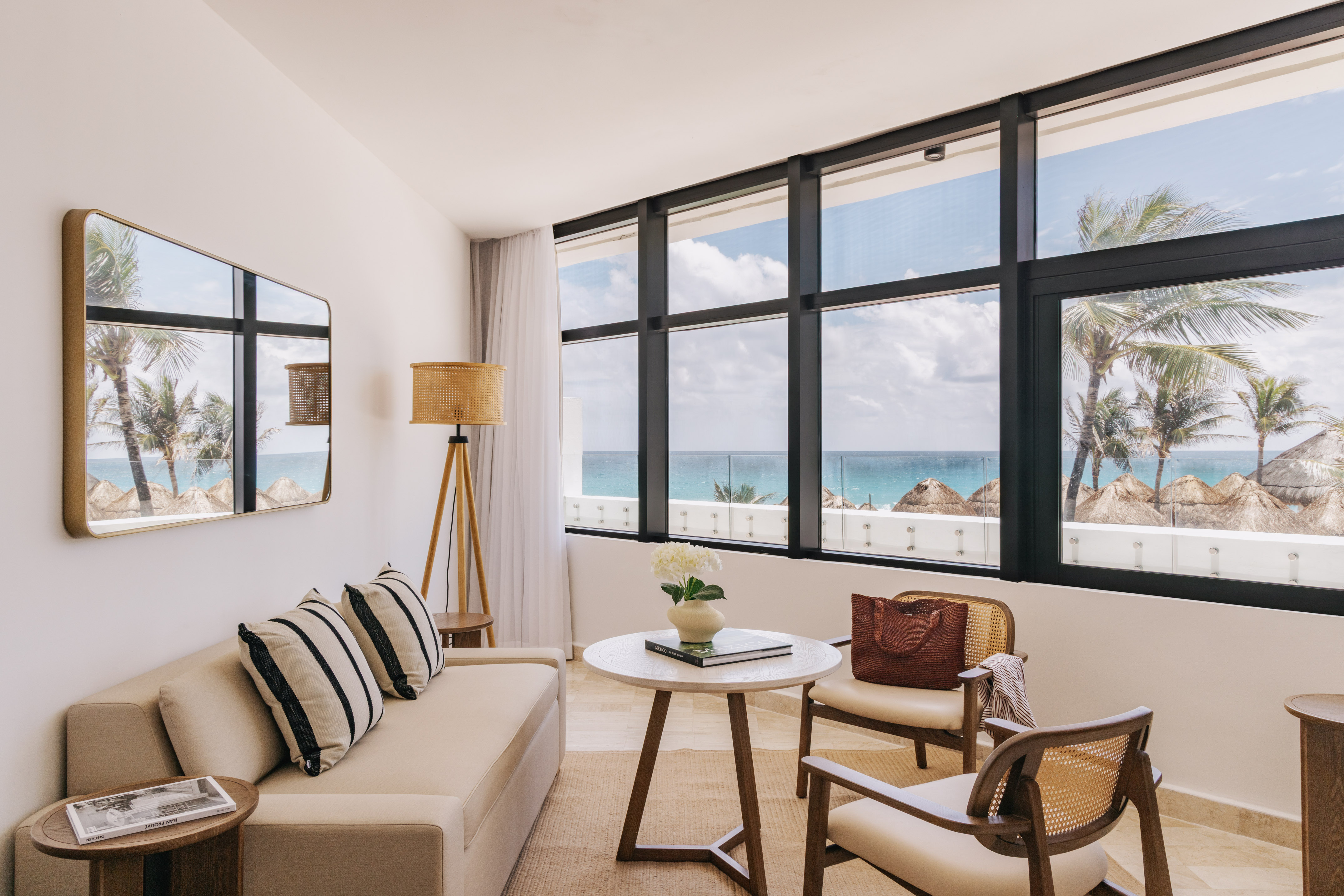 Bright oceanfront hotel living room with palm tree views and modern decor.