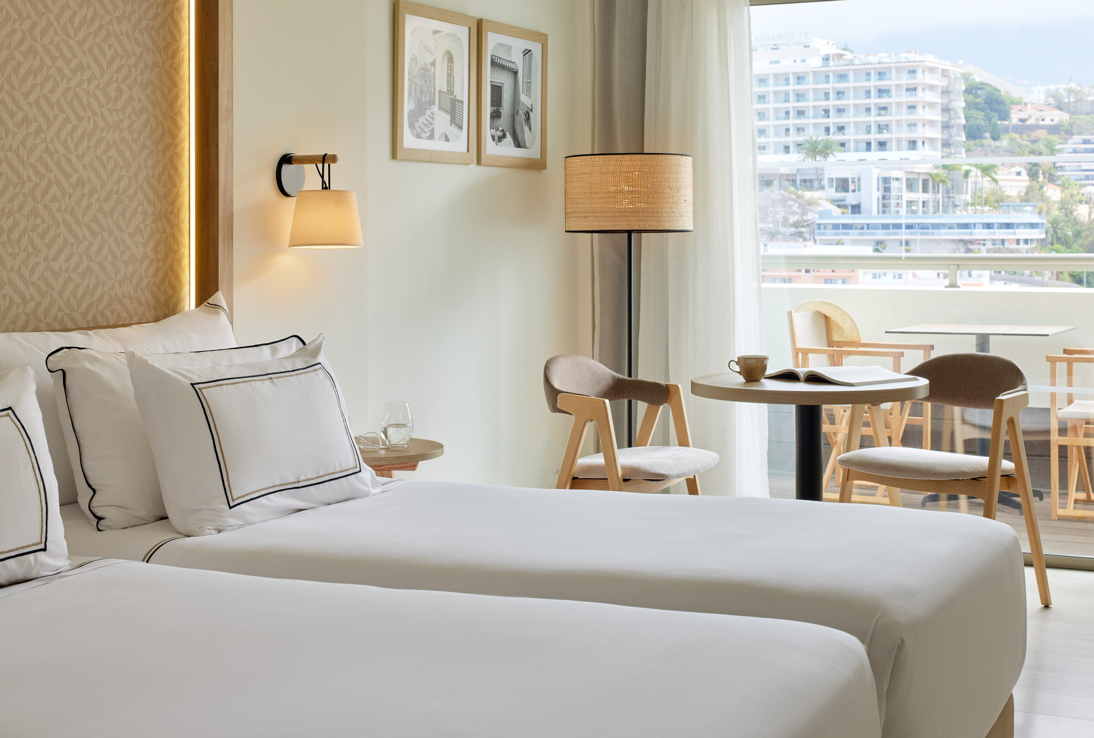 Relaxing hotel room with twin beds, balcony, and scenic resort town view.