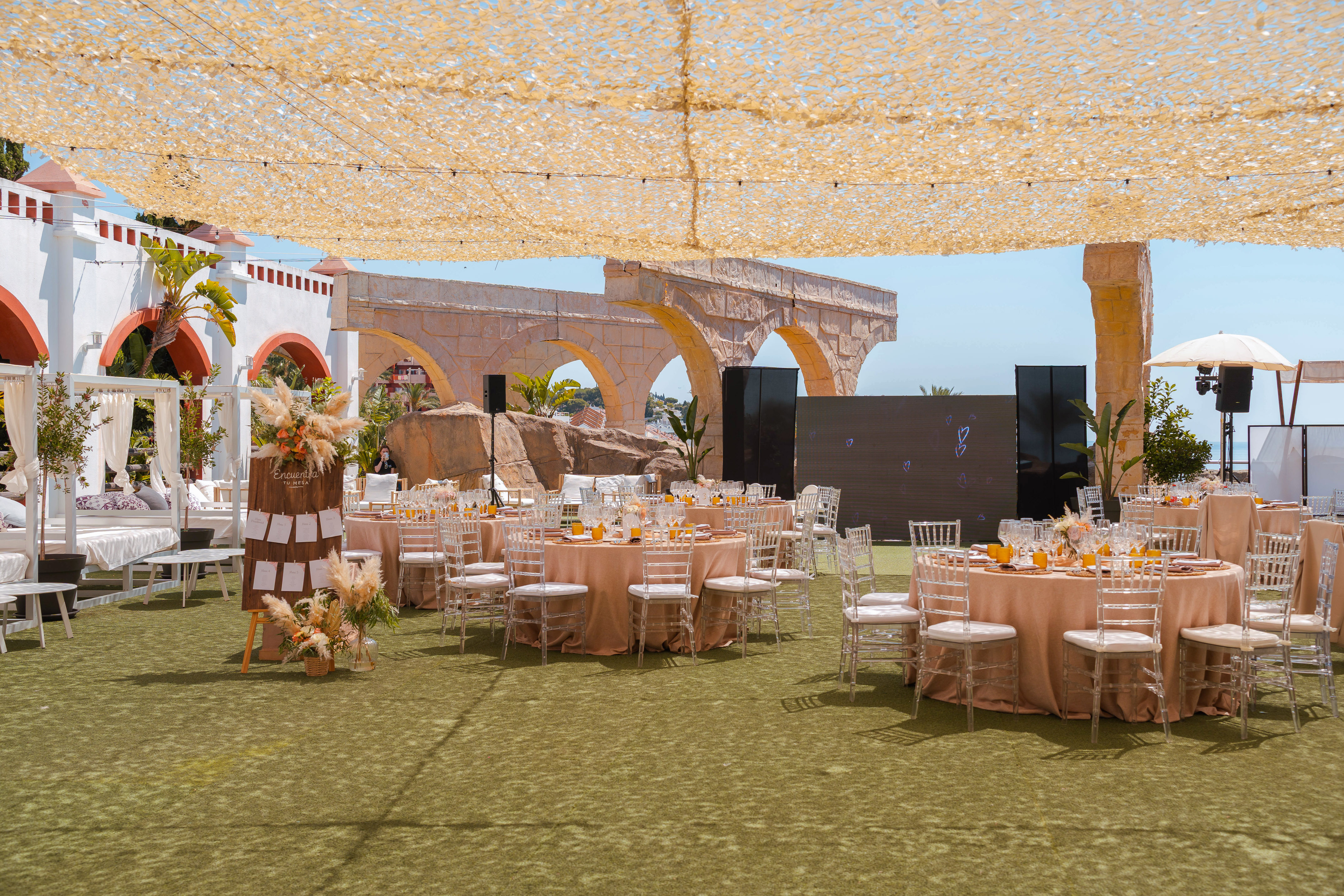 Outdoor reception tables, ghost chairs, pampas grass decor, and stone arches.