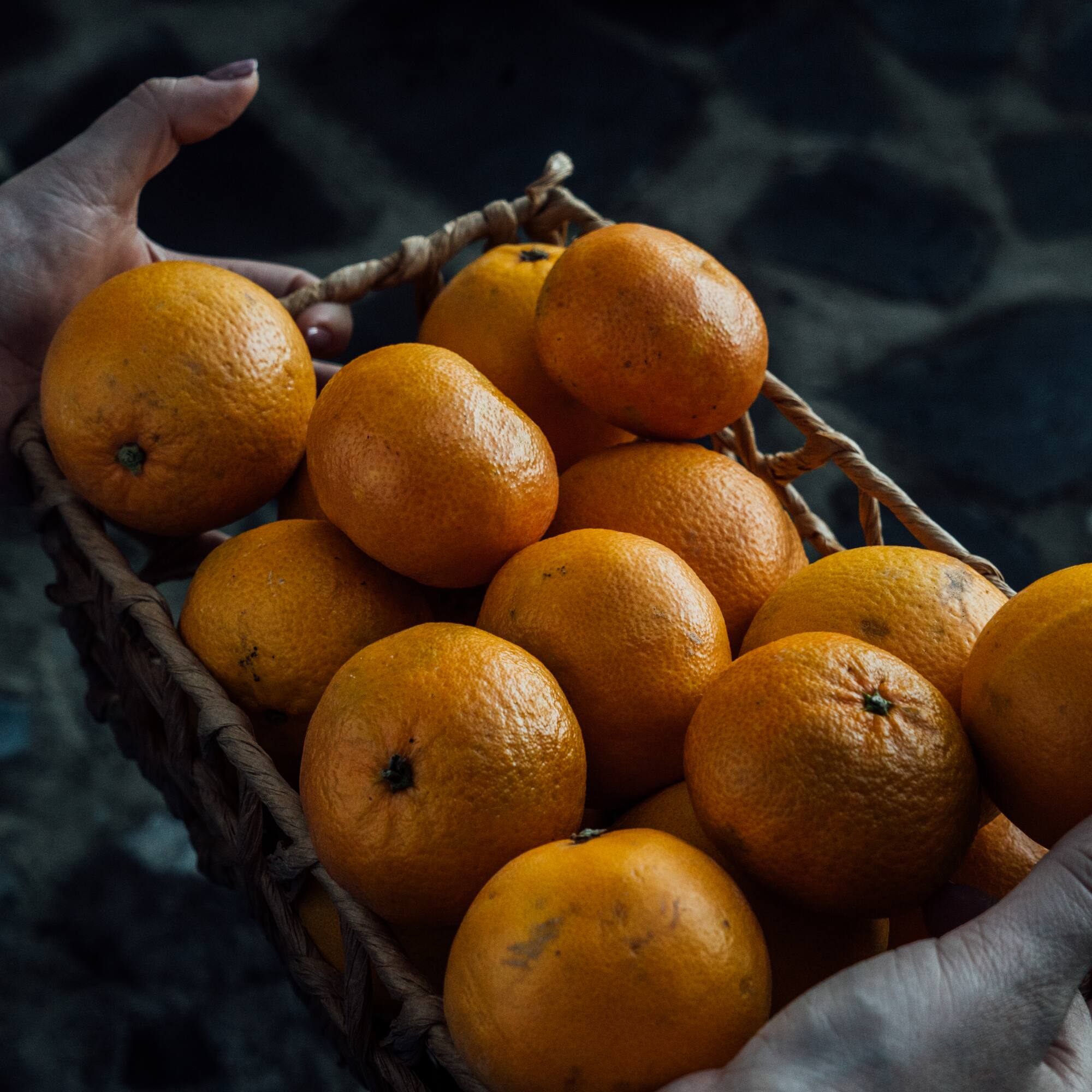 a person holding a basket of oranges