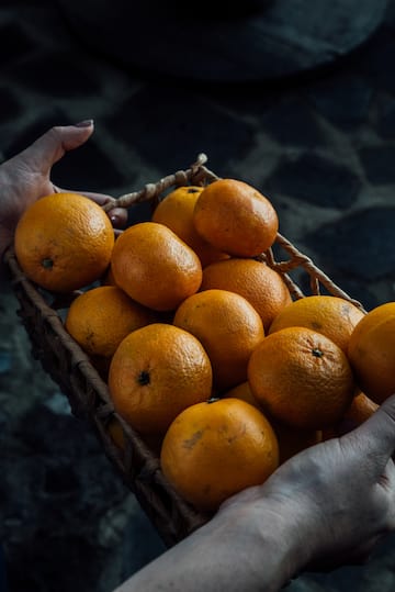 a person holding a basket of oranges