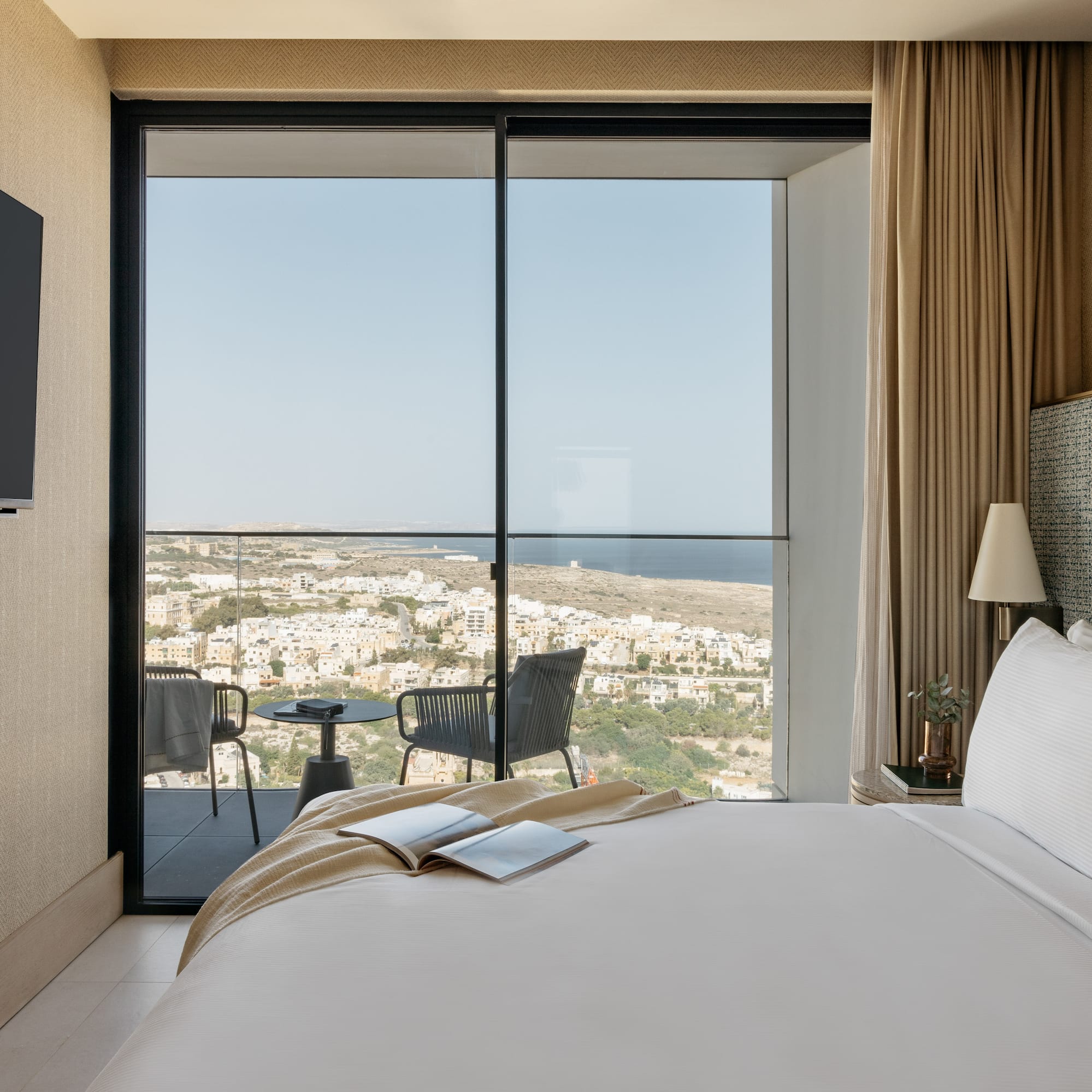 a bedroom with a view of the city from the window