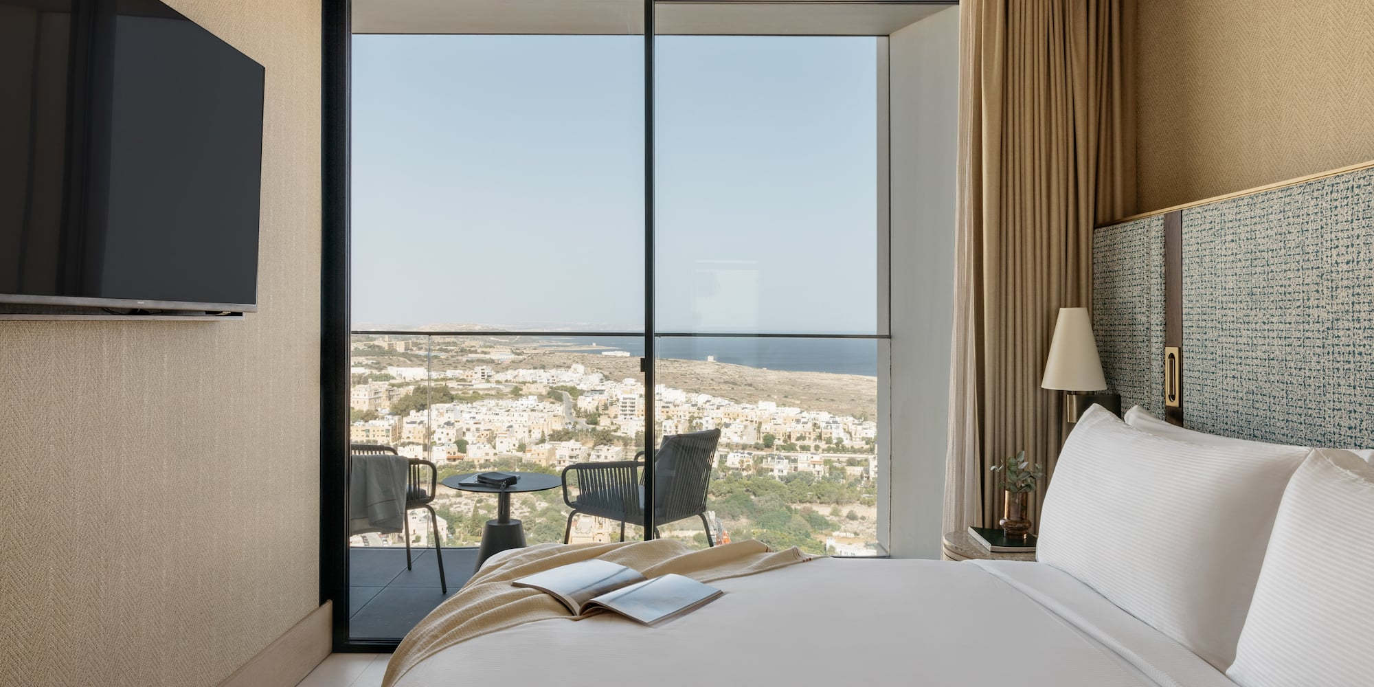 a bedroom with a view of the city from the window