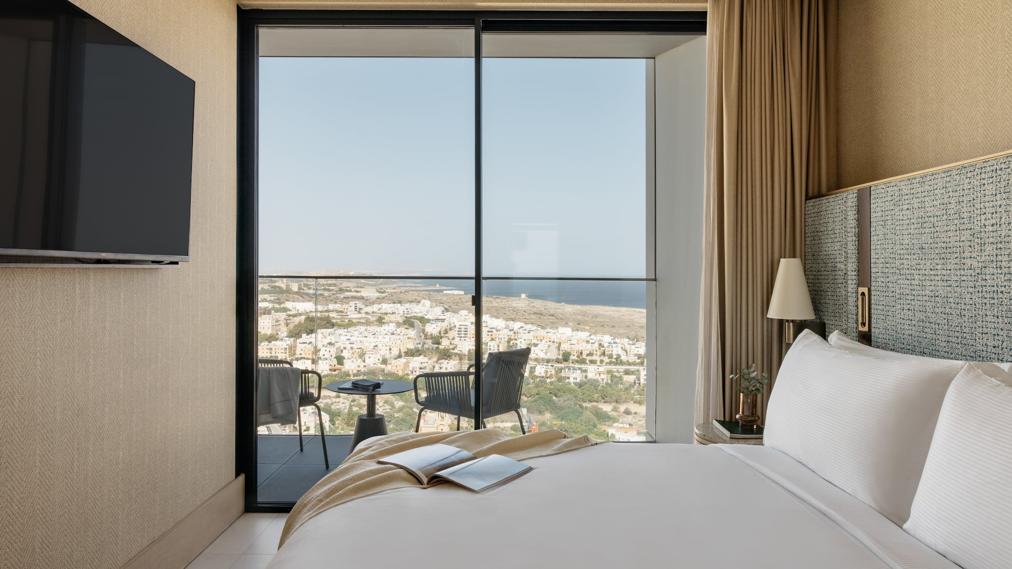 a bedroom with a view of the city from the window