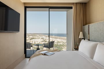 a bedroom with a view of the city from the window