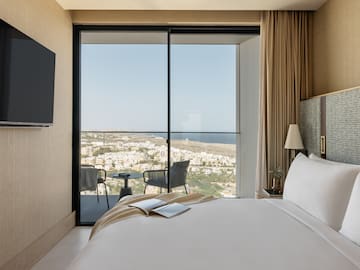 a bedroom with a view of the city from the window