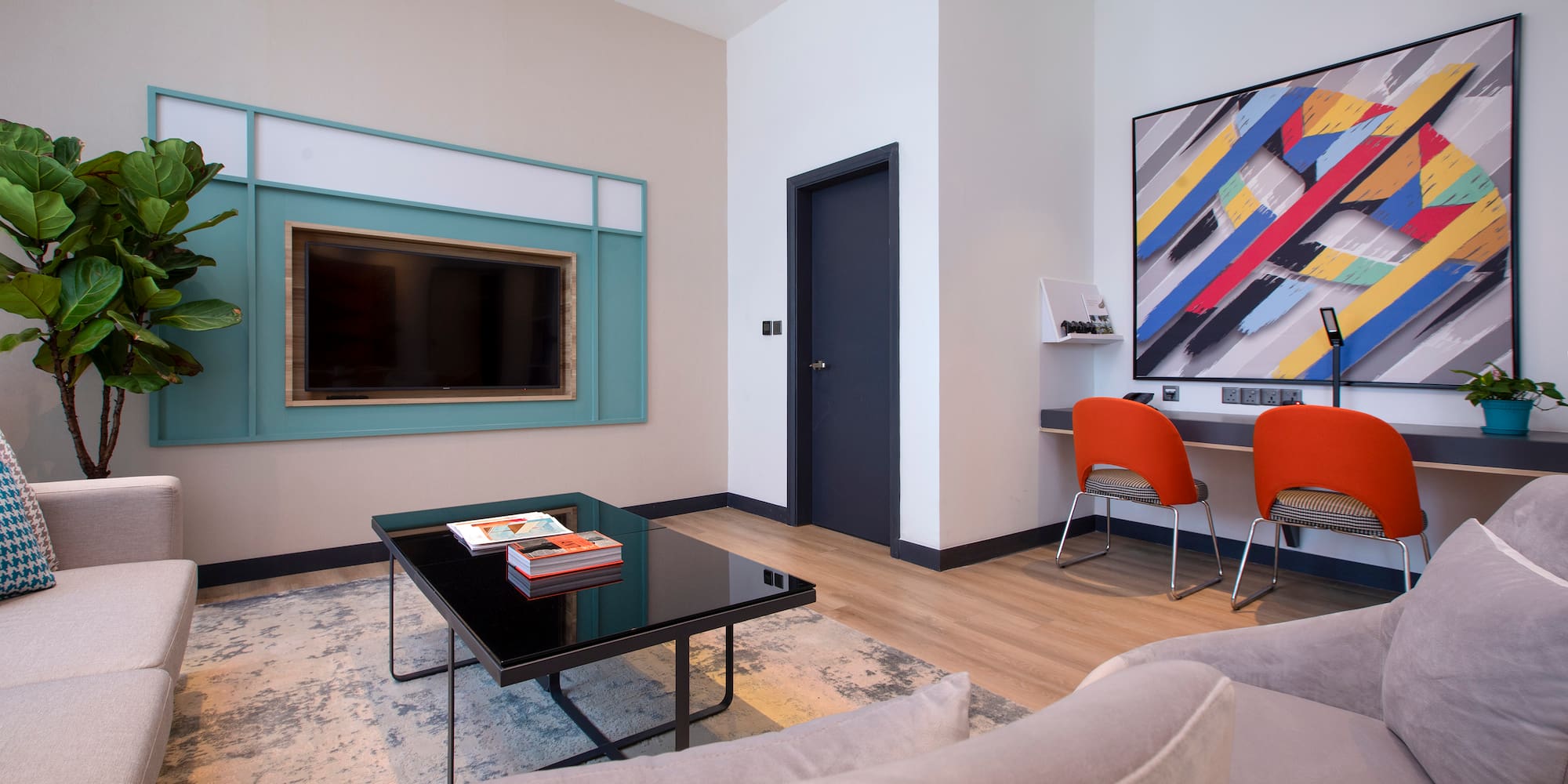 a living room with a black coffee table and a painting on the wall