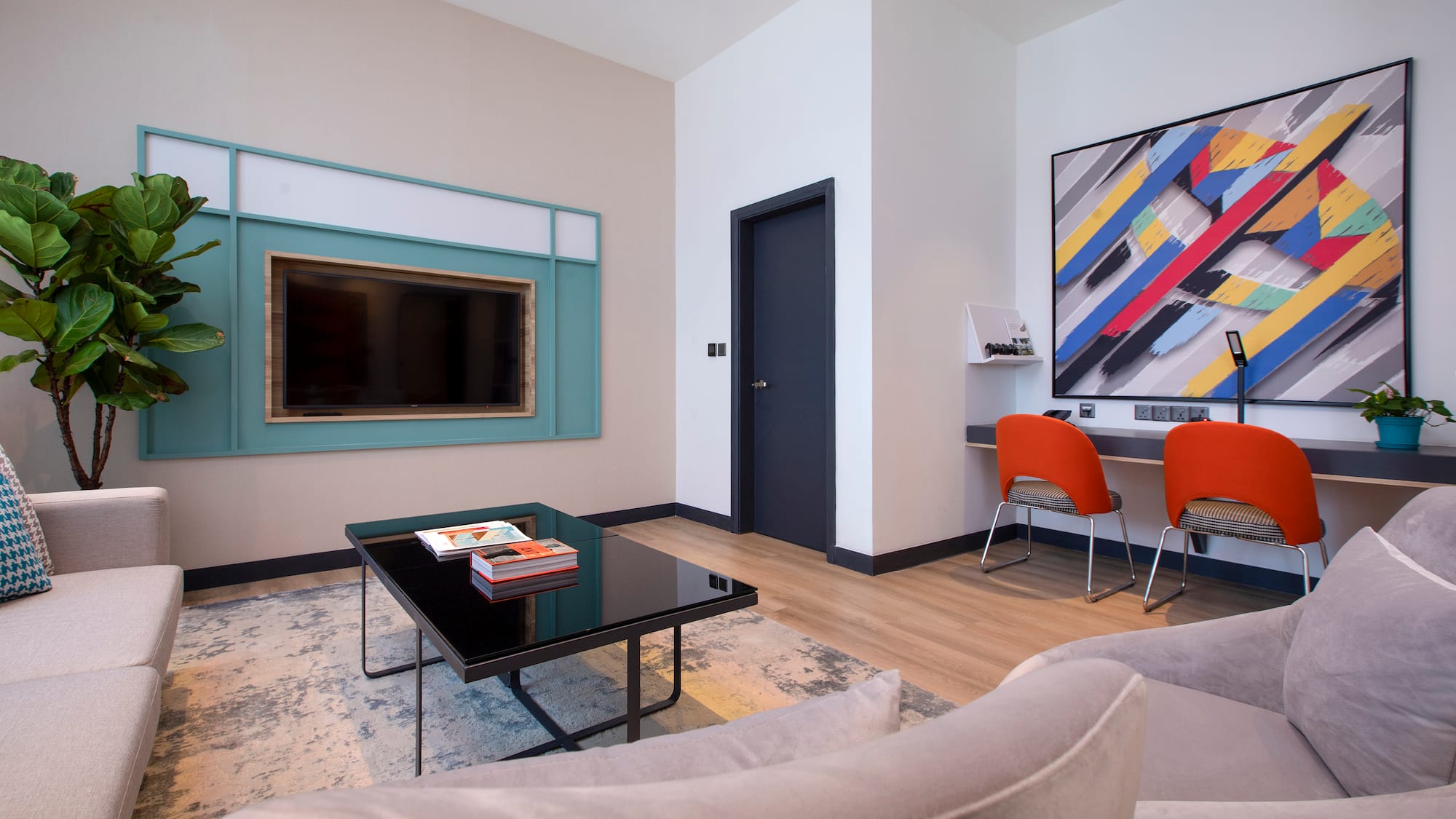 a living room with a black coffee table and a painting on the wall