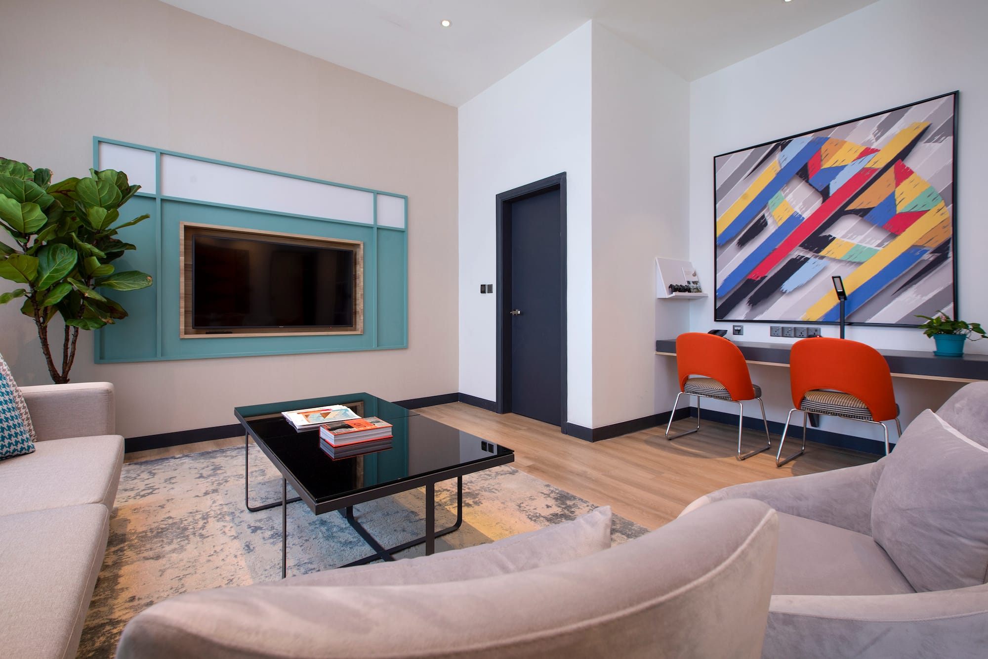a living room with a black coffee table and a painting on the wall