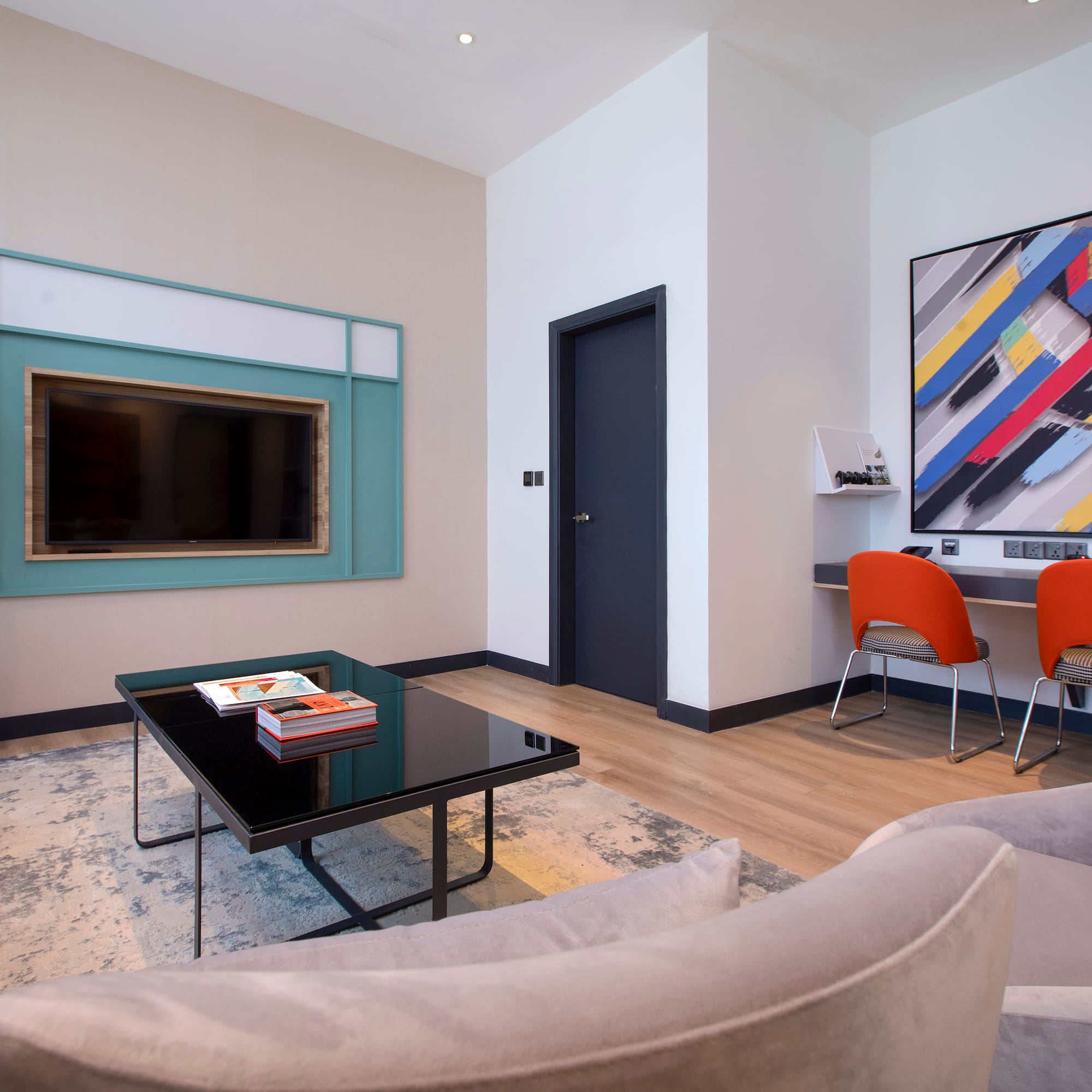 a living room with a black coffee table and a painting on the wall