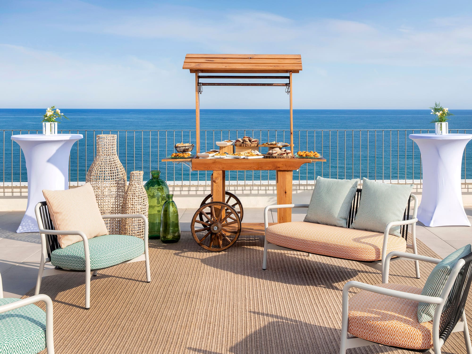 a table with food on it and chairs on a deck with a body of water