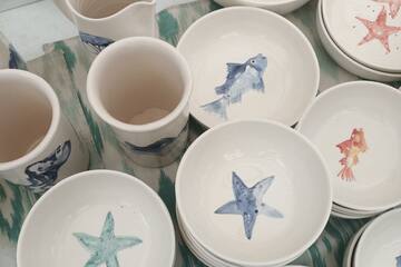 a group of bowls and mugs with fish and starfish painted on them