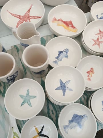 a group of bowls and mugs with fish and starfish painted on them