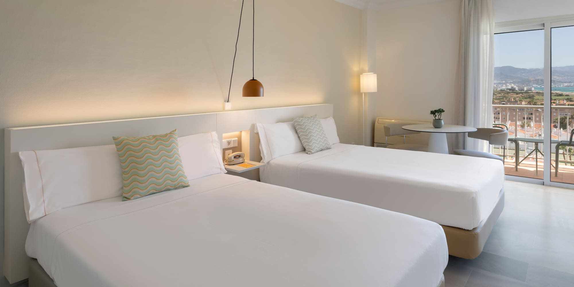 Habitación doble hotel, camas individuales, balcón y vistas costeras.