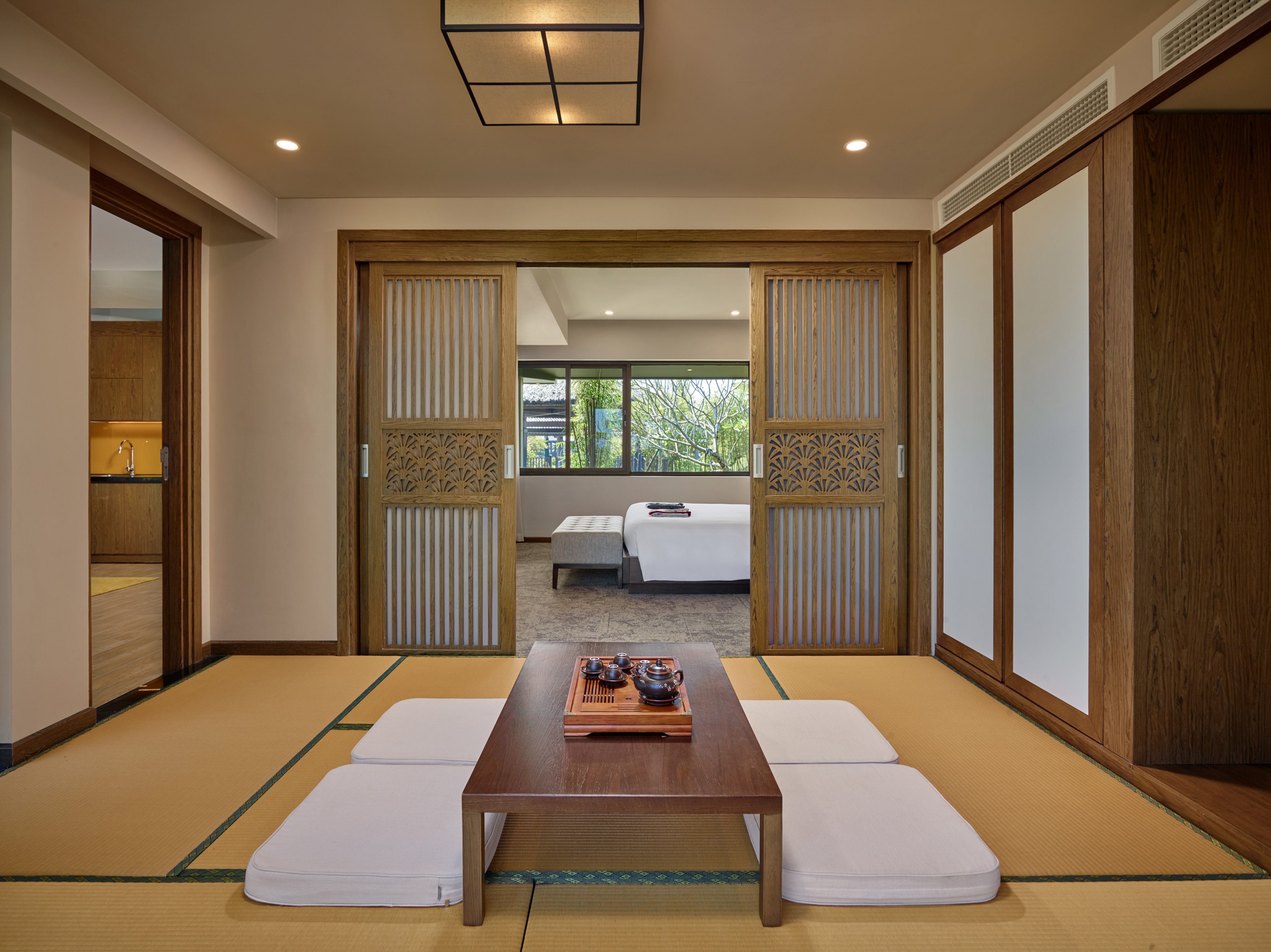 Japanese tatami room, tea table, cushions, and sliding doors open to bedroom.