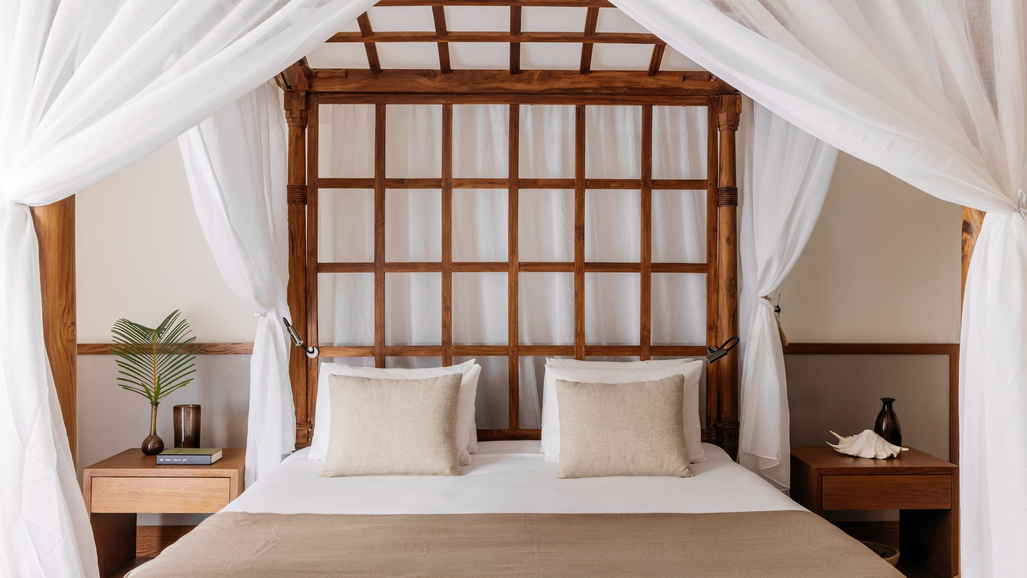 a bed with white curtains and a wooden canopy over it