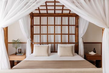 a bed with white curtains and a wooden canopy over it