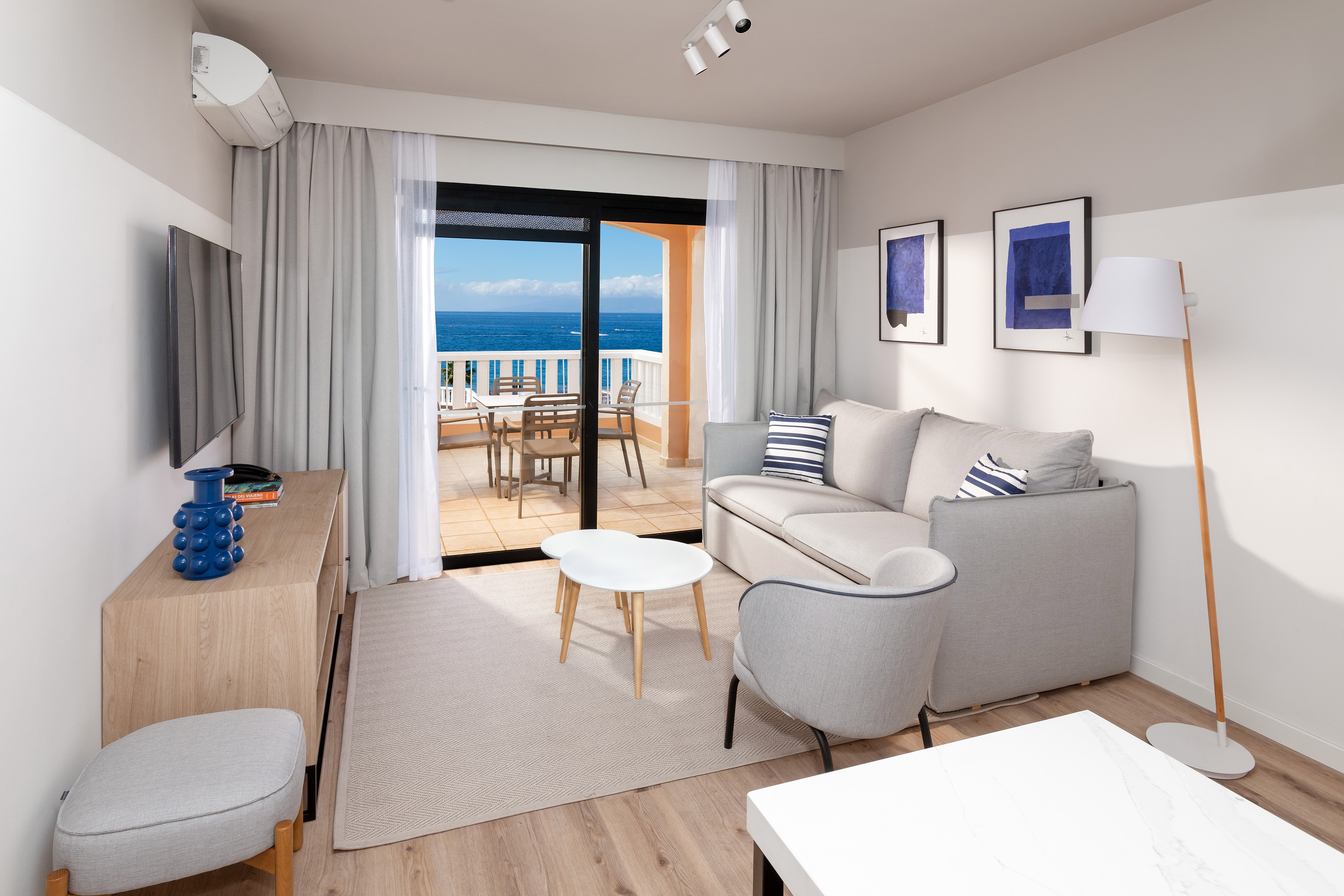 Modern apartment living room with sea view balcony and grey sofa.