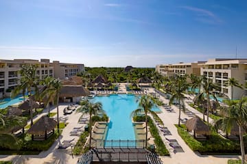 a pool with palm trees and a building with a blue sky