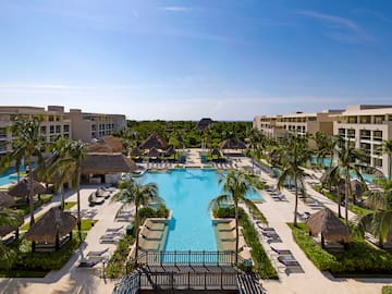 a pool with palm trees and a building with a blue sky