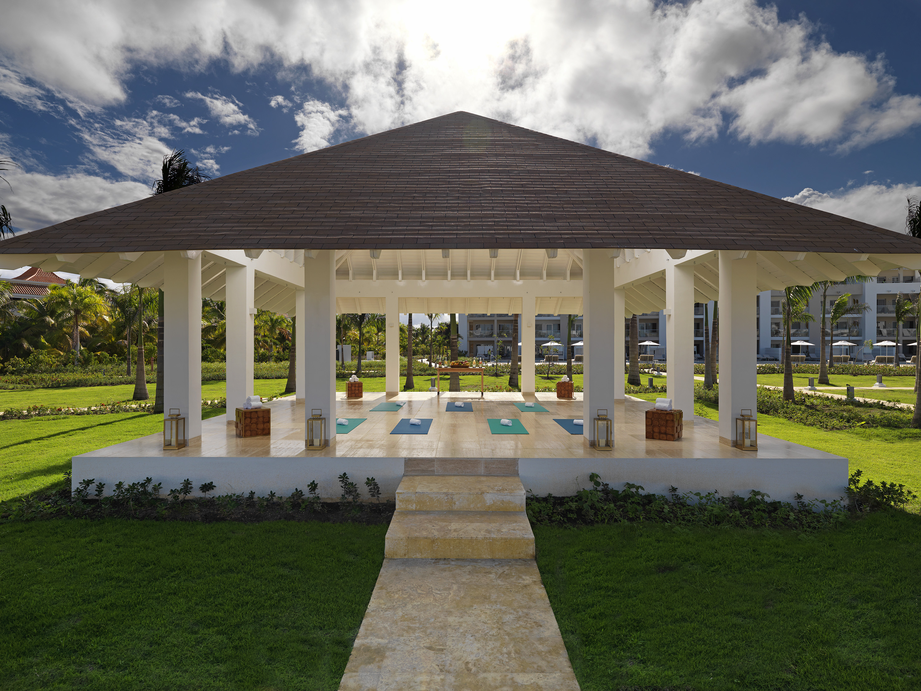 a gazebo with yoga mats and a path in a park