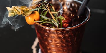 a copper cup with a straw and a plant on top