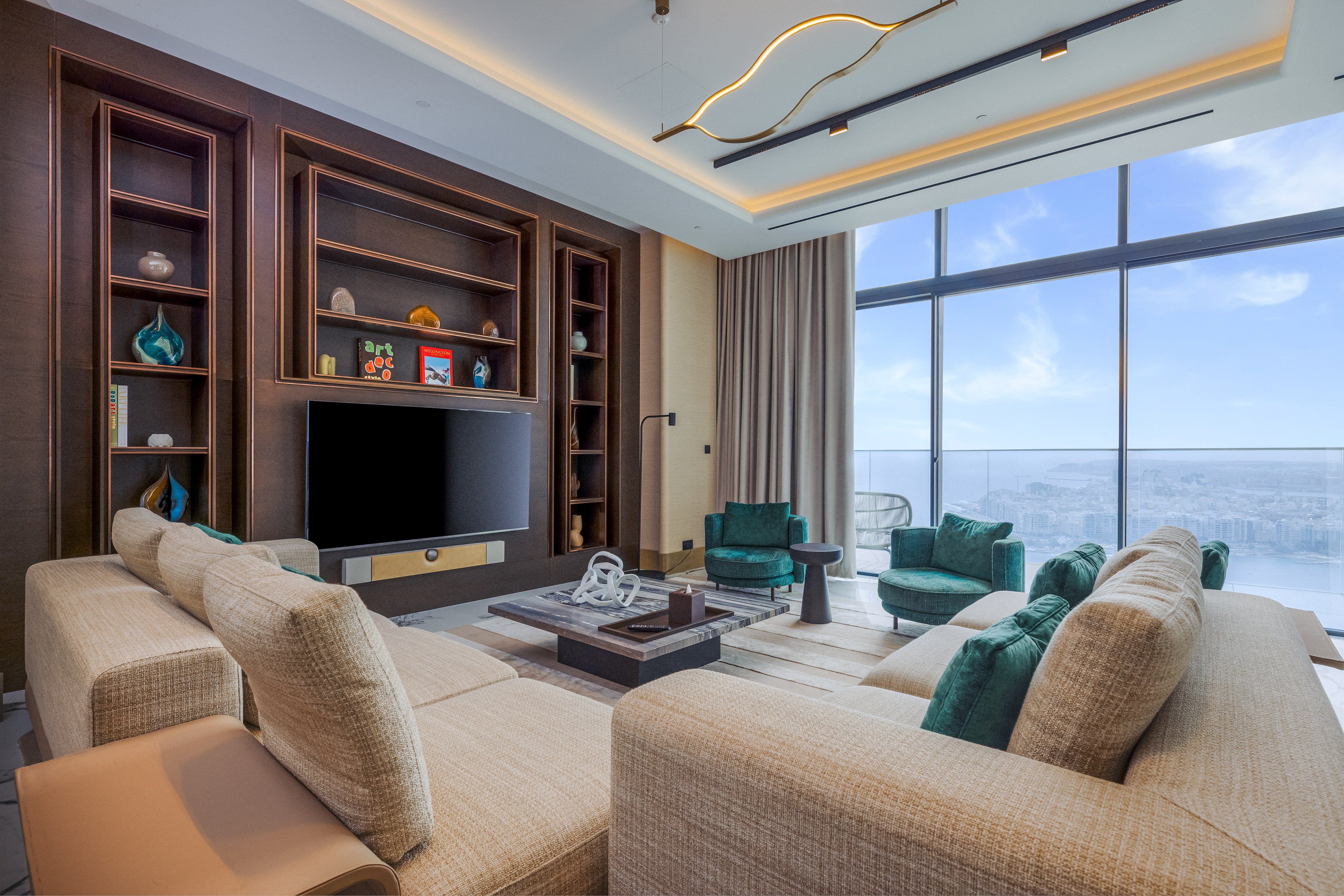 Contemporary living room with beige sofa, green armchairs, media wall, and city view.