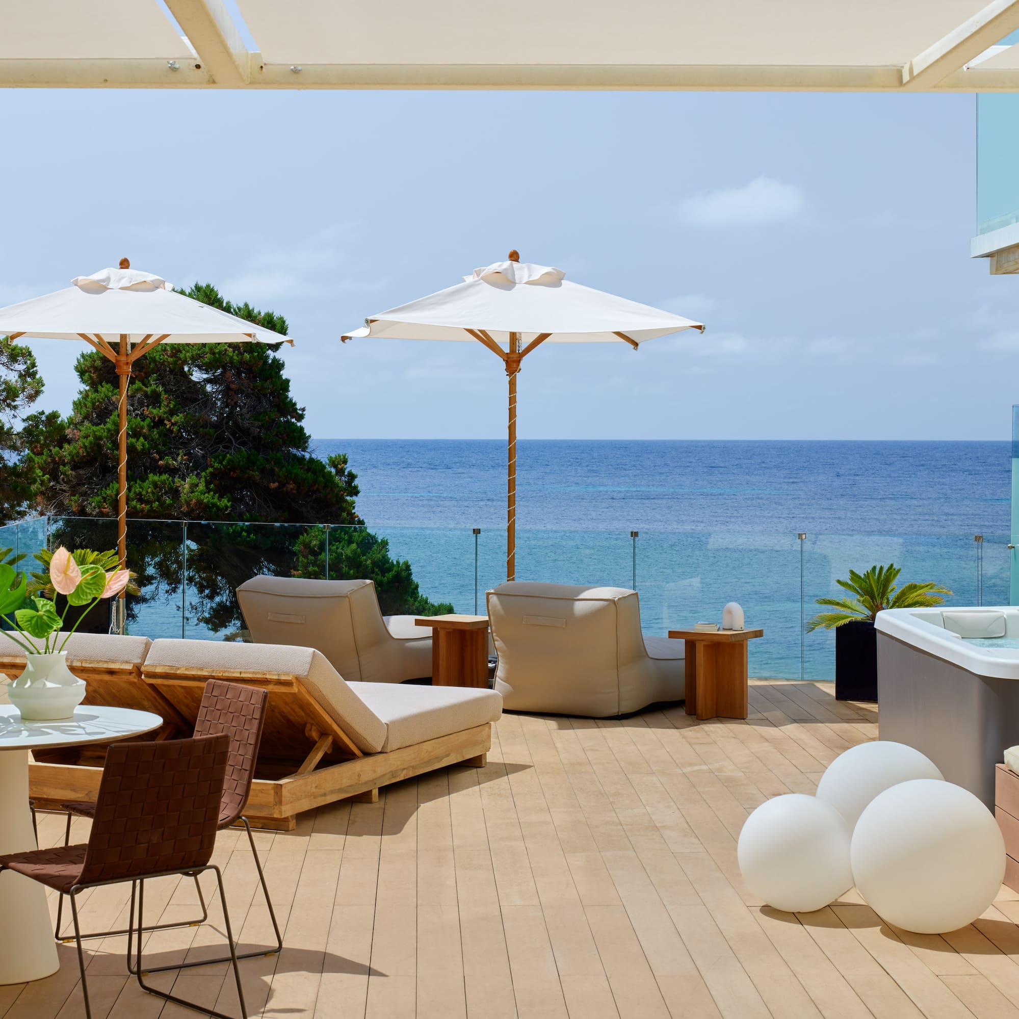 Modern oceanfront terrace with hot tub, sun loungers, and dining.