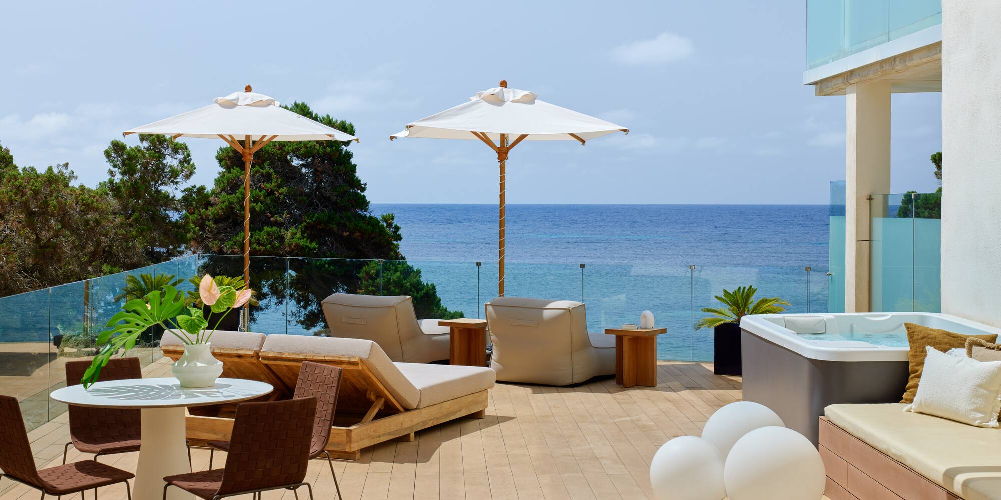 Modern oceanfront terrace with hot tub, sun loungers, and dining.