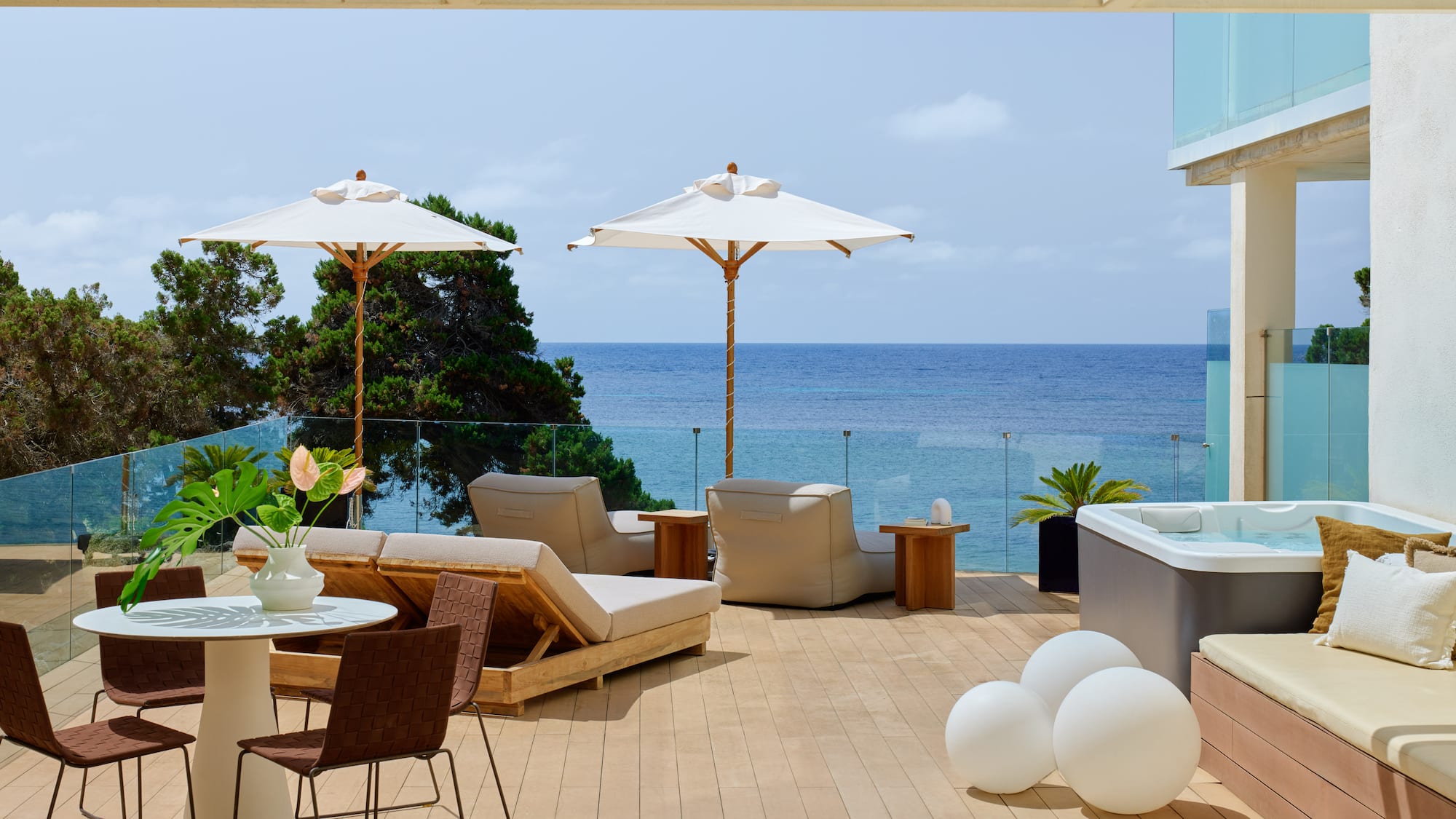 Modern oceanfront terrace with hot tub, sun loungers, and dining.
