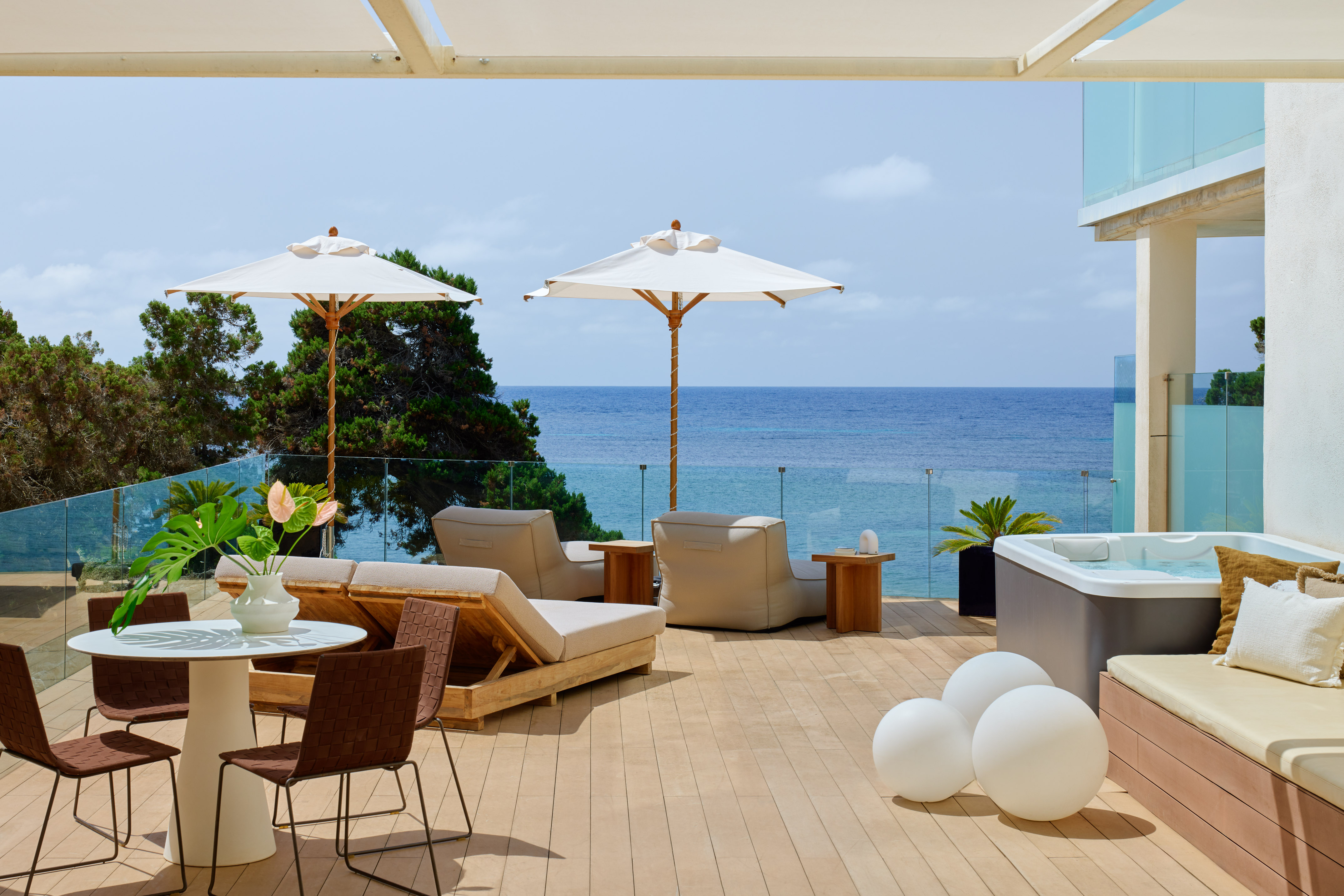 Modern oceanfront terrace with hot tub, sun loungers, and dining.