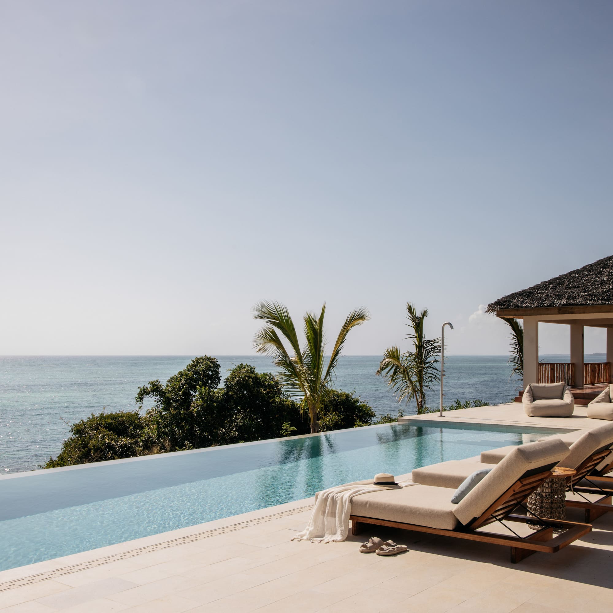 a pool with lounge chairs and a gazebo overlooking the ocean