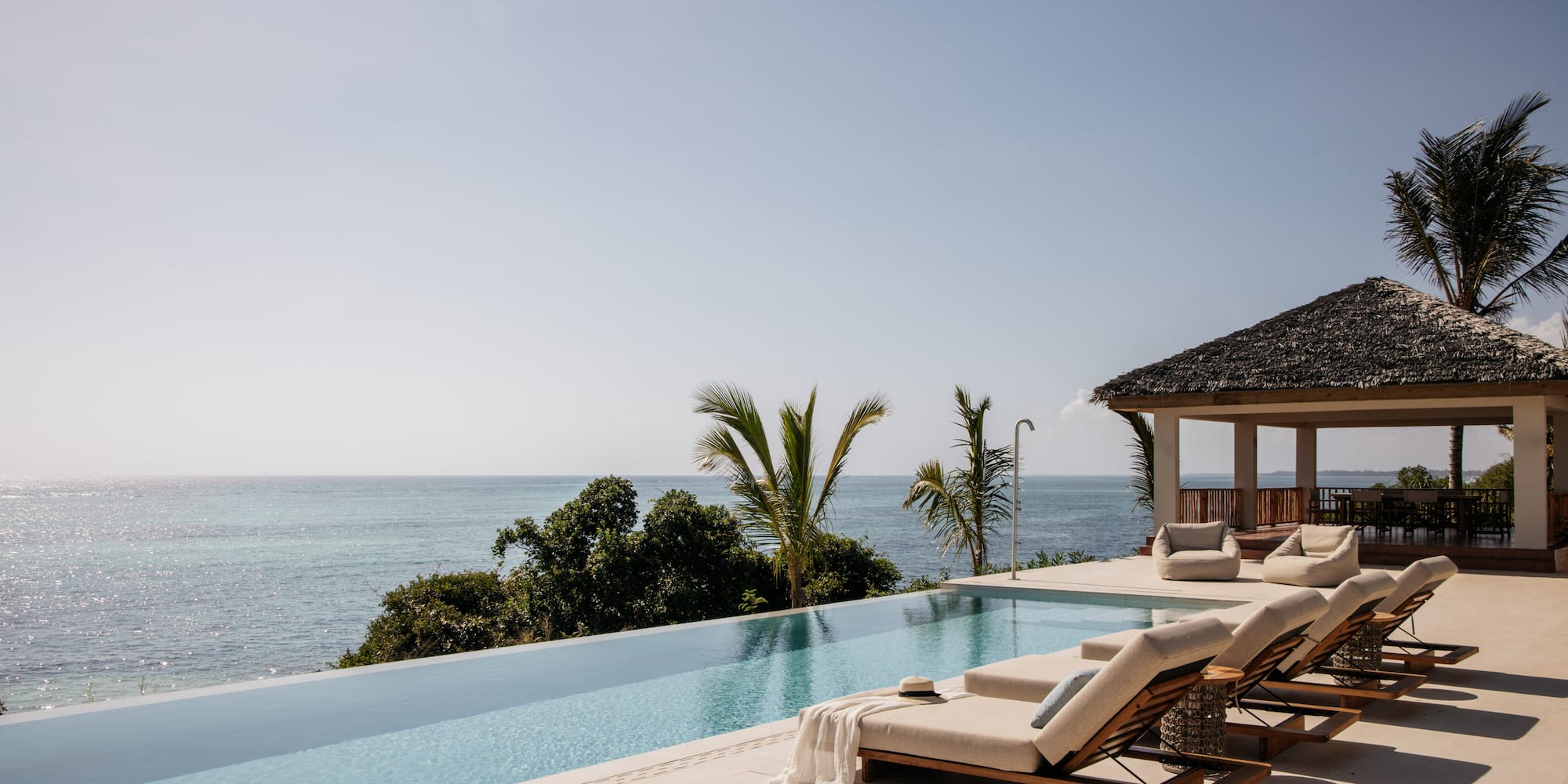 a pool with lounge chairs and a gazebo overlooking the ocean