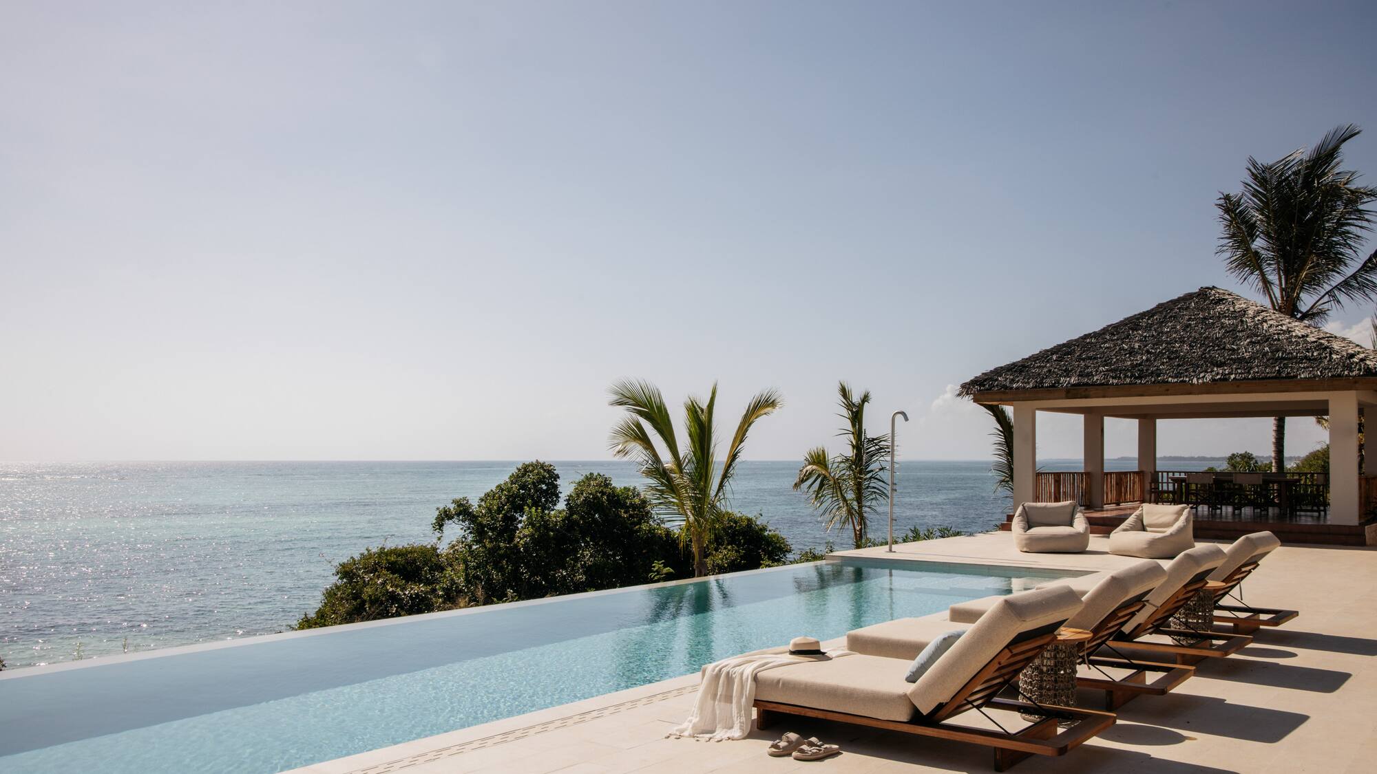 a pool with lounge chairs and a gazebo overlooking the ocean