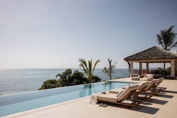 a pool with lounge chairs and a gazebo overlooking the ocean