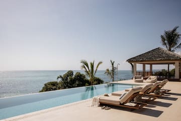 a pool with lounge chairs and a gazebo overlooking the ocean
