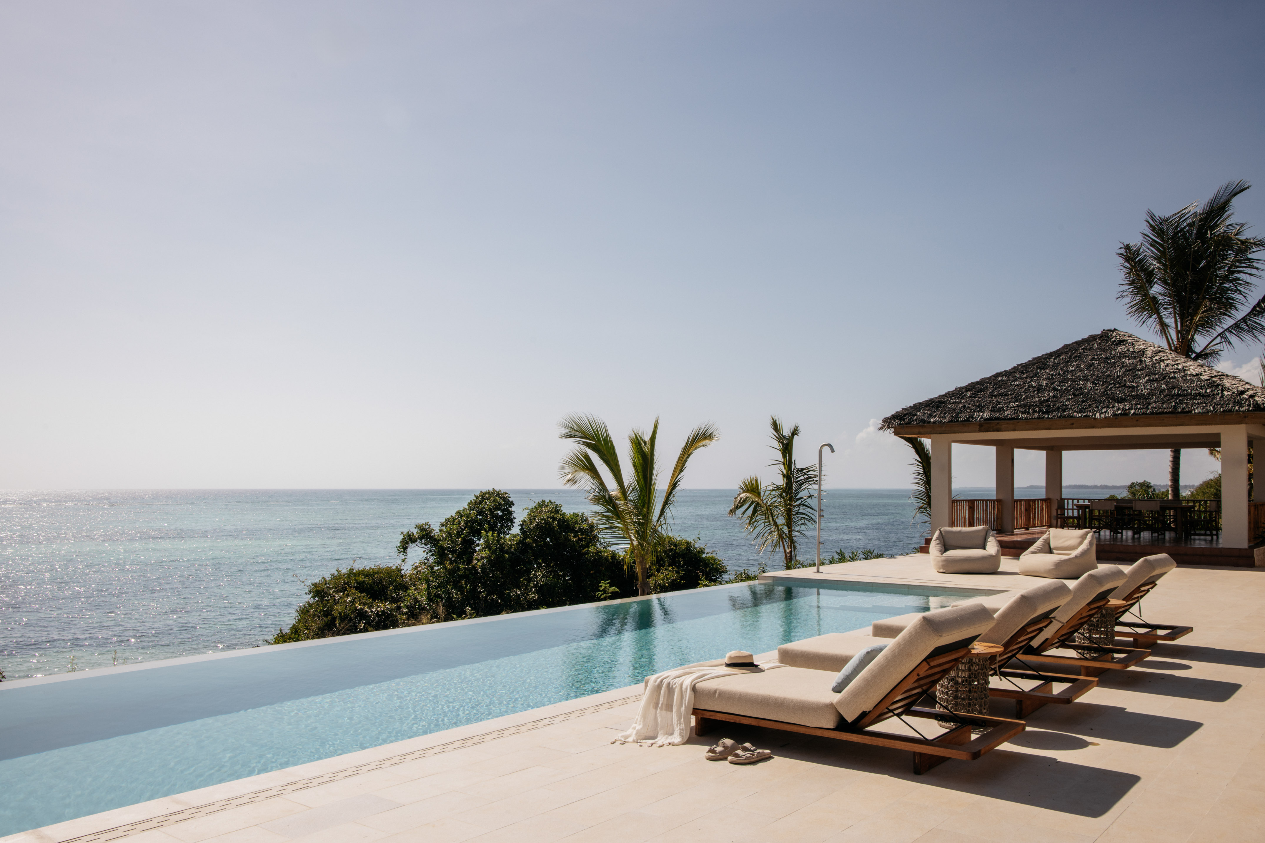 a pool with lounge chairs and a gazebo overlooking the ocean