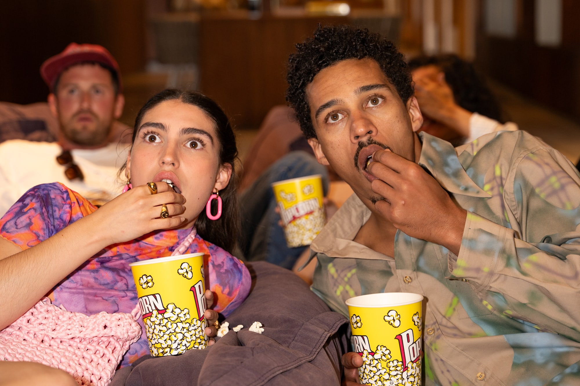 a group of people sitting on a couch eating popcorn