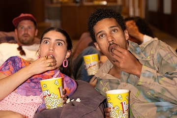 a group of people sitting on a couch eating popcorn