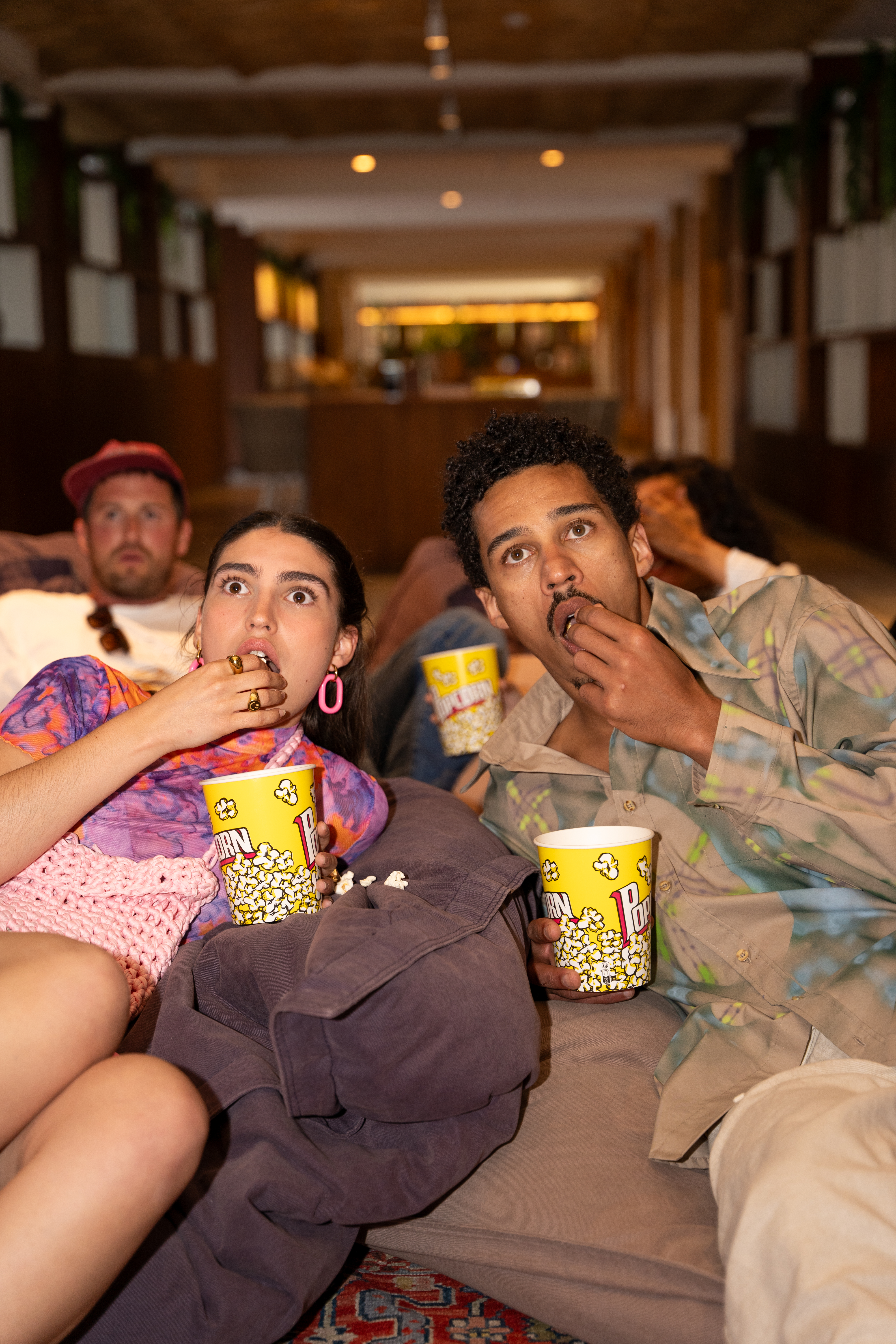 a group of people sitting on a couch eating popcorn