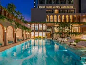 a swimming pool with lounge chairs and trees in front of a building