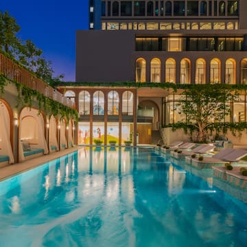 a swimming pool with lounge chairs and trees in front of a building