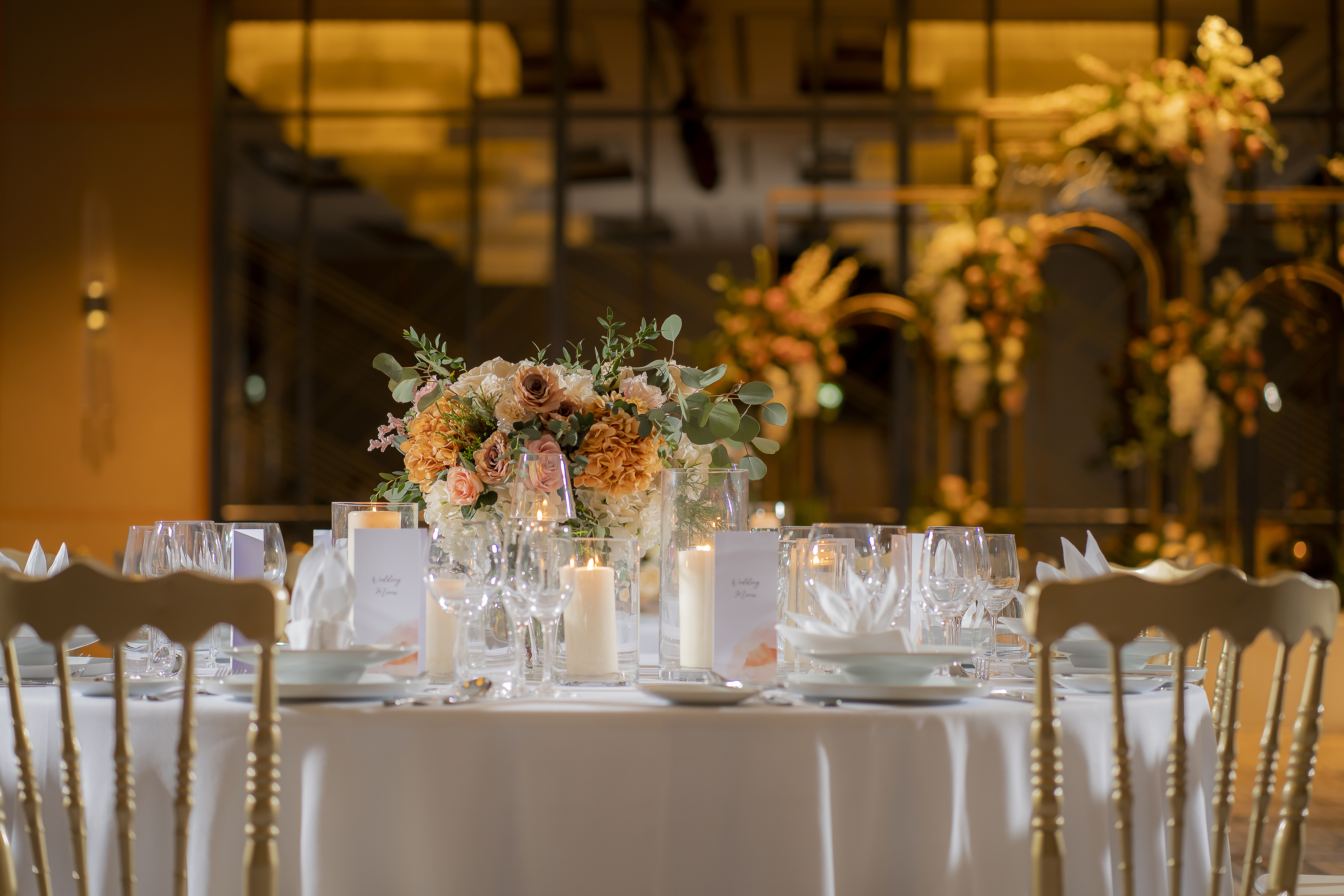 Elegant wedding reception table with floral centerpiece and warm candlelight.