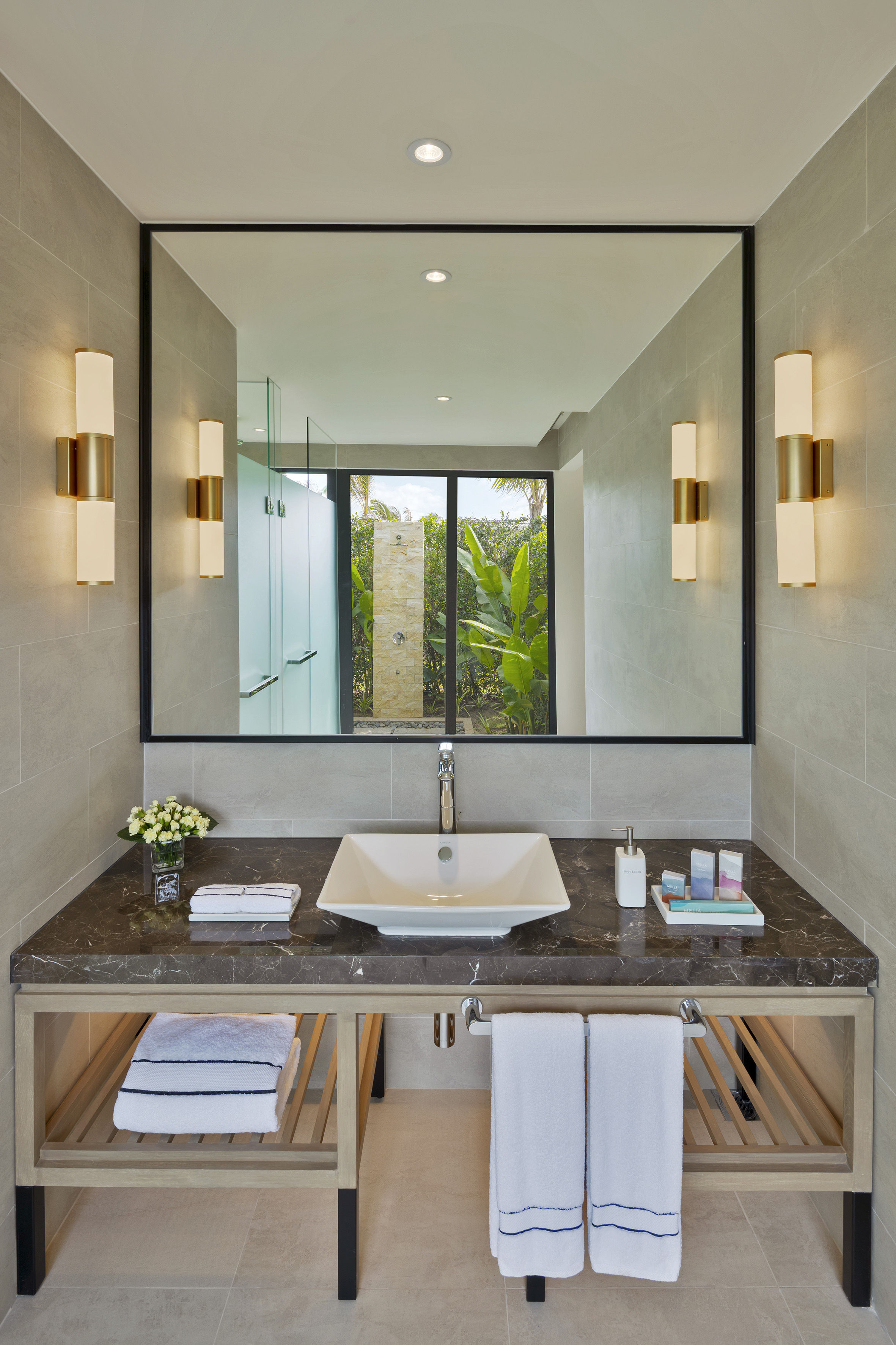 Modern bathroom vanity, marble counter, sink, mirror, and tropical shower view.