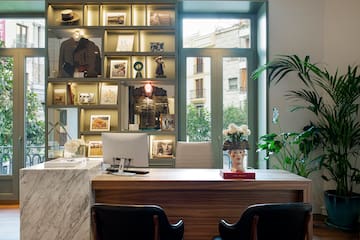 a desk with a computer and a display case in front of a window