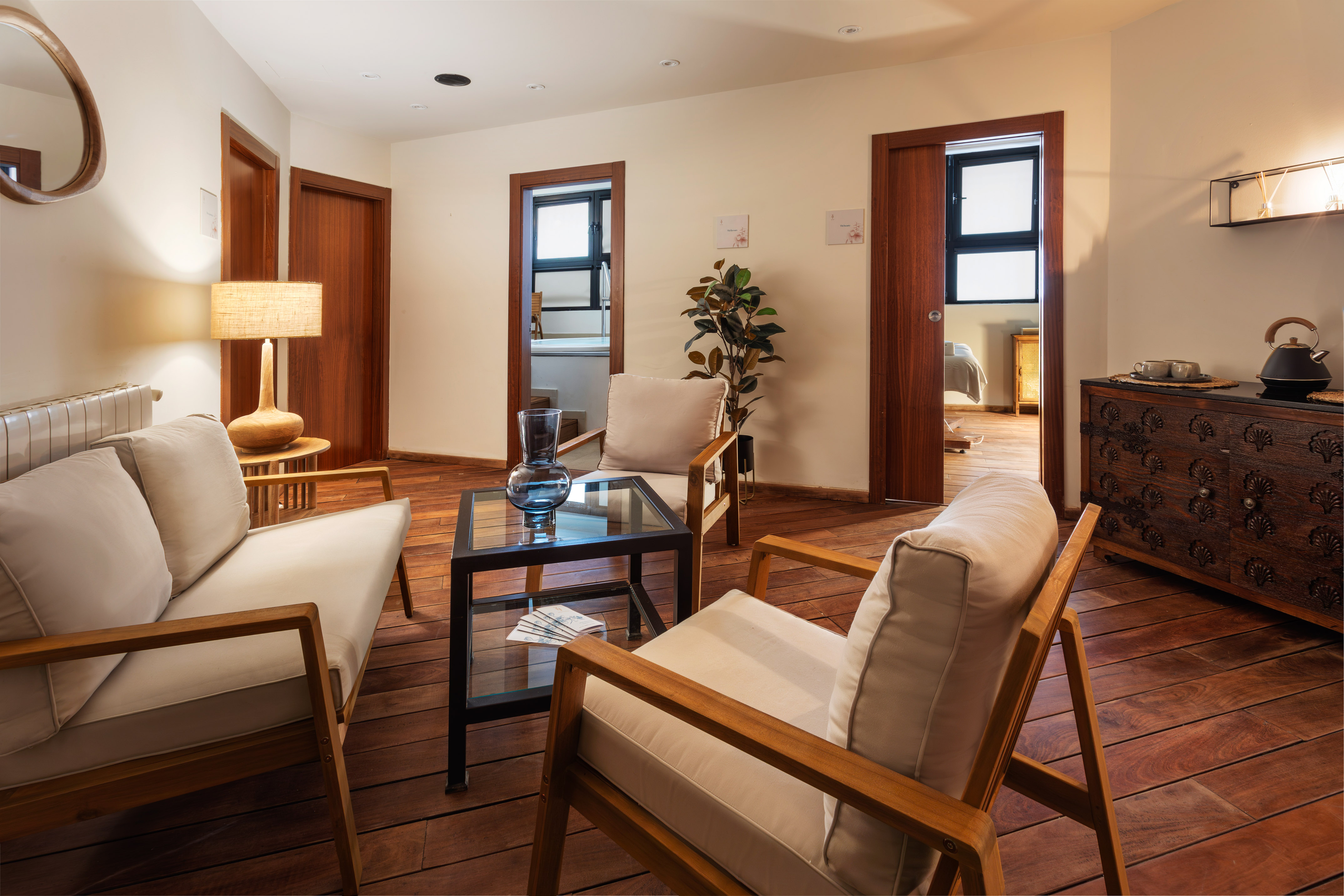 Stylish living room with wooden floors, beige chairs, and glass coffee table.