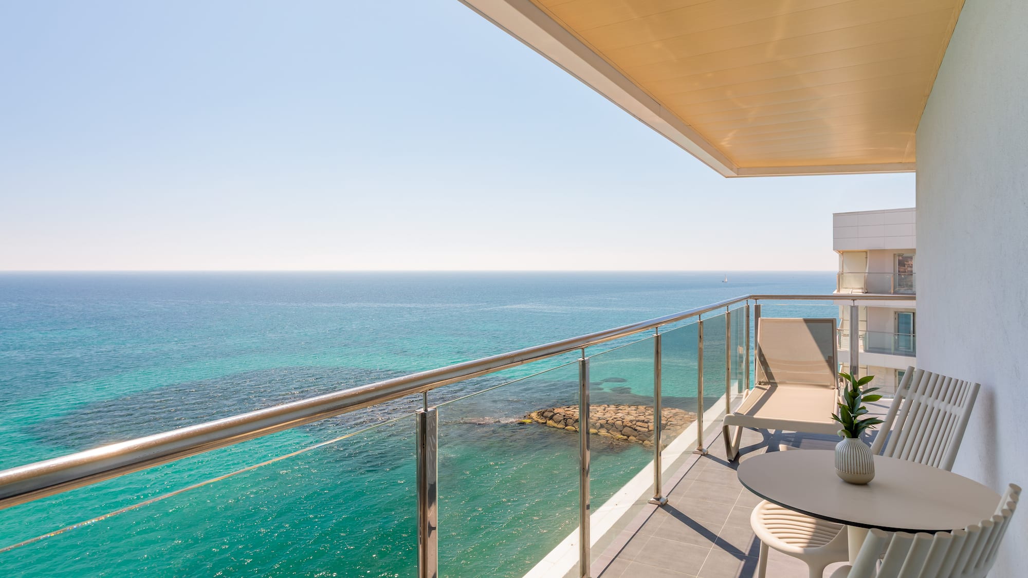 a table and chairs on a balcony overlooking the ocean