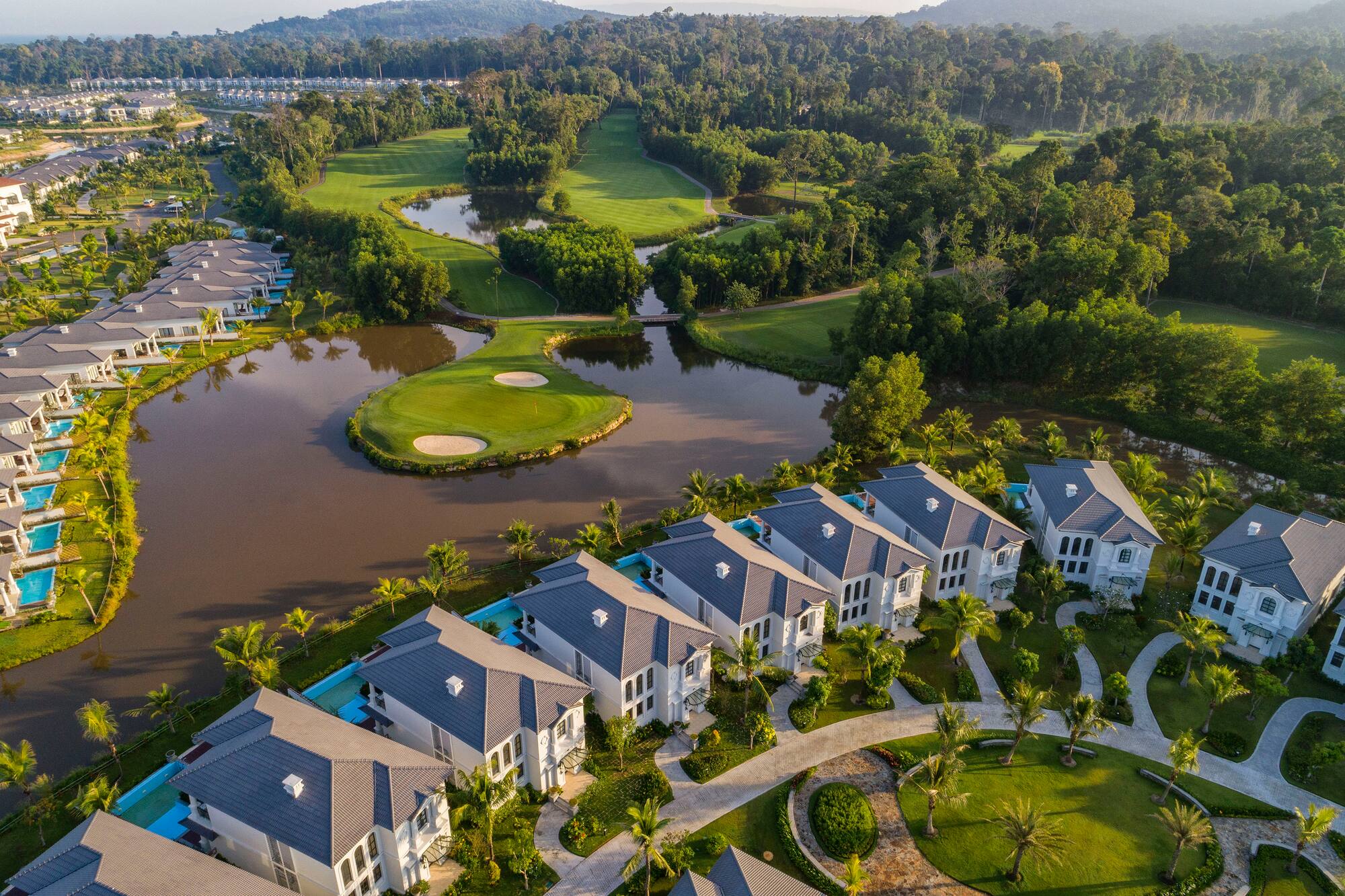 Luxury villas and golf course resort with lakes and tropical landscape.