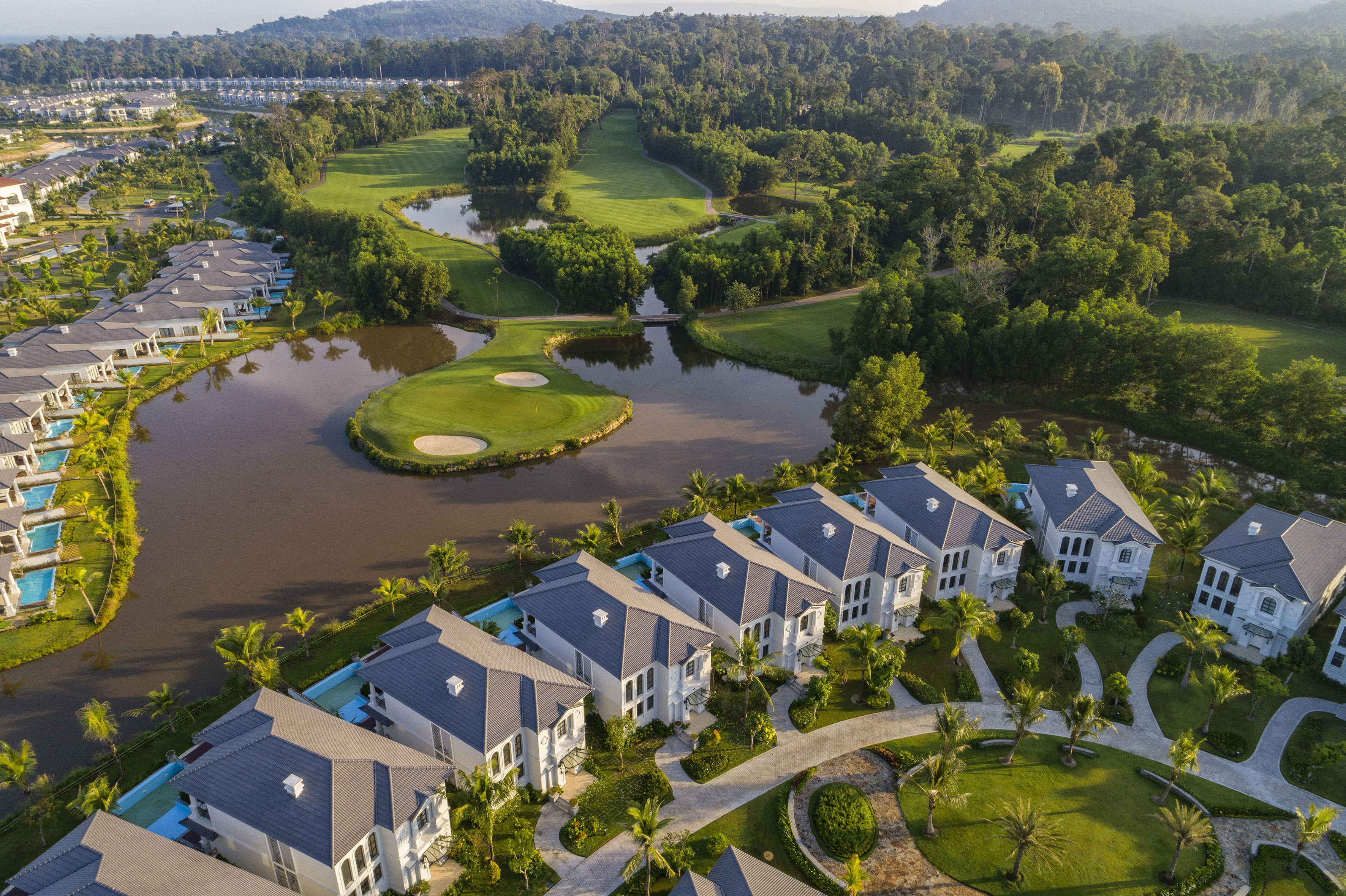 Luxury villas and golf course resort with lakes and tropical landscape.