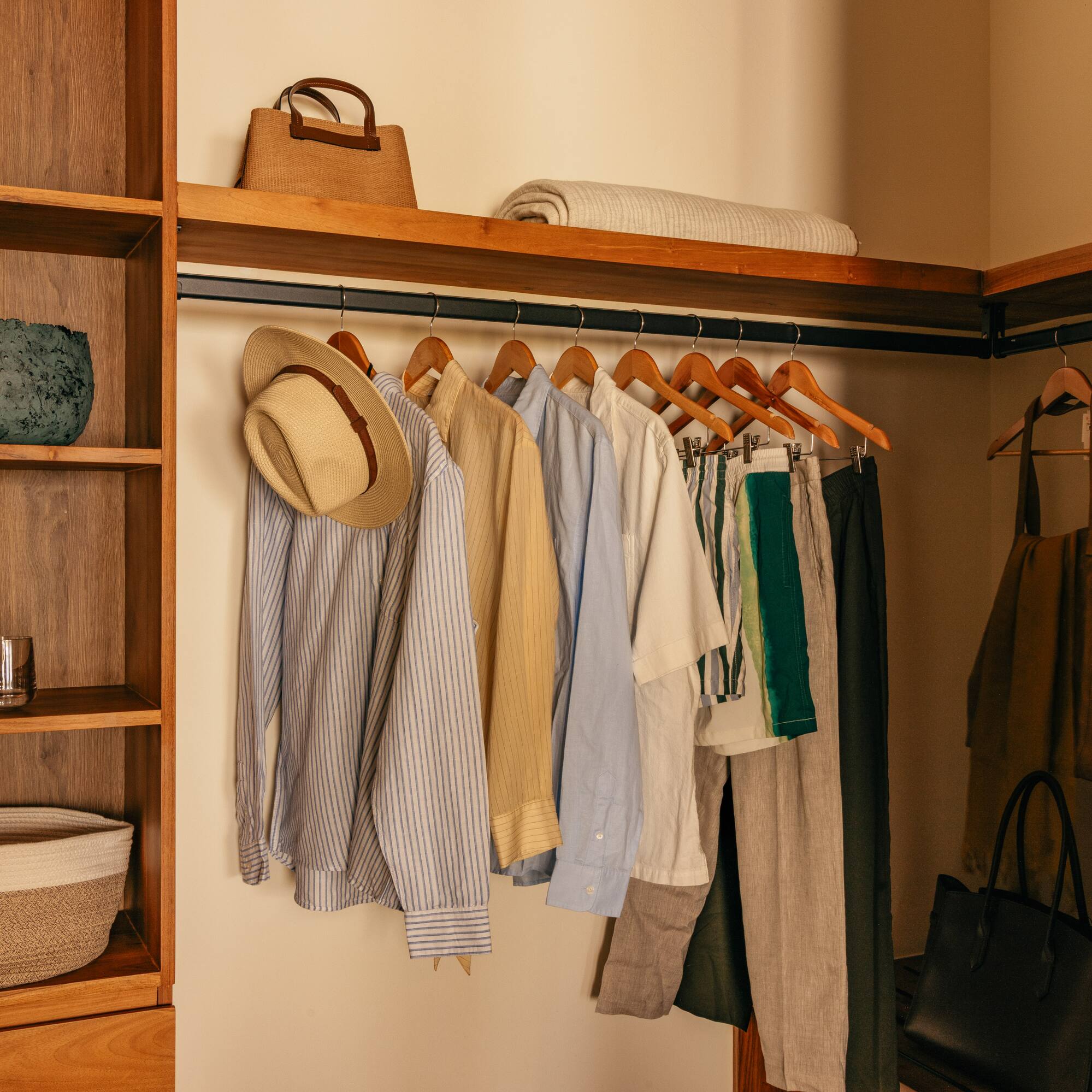 a closet with clothes on swingers and a shelf